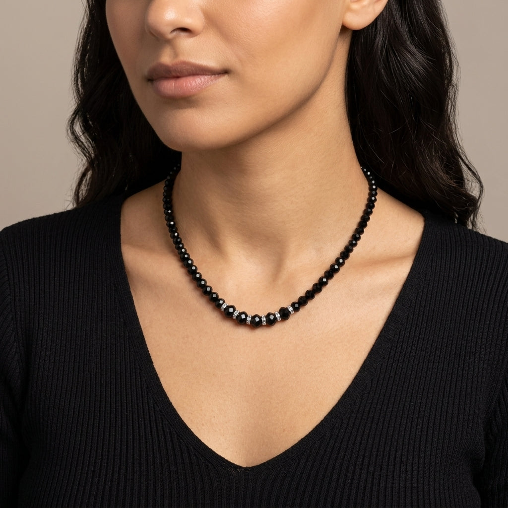 Woman wearing a black beaded necklace against a neutral background