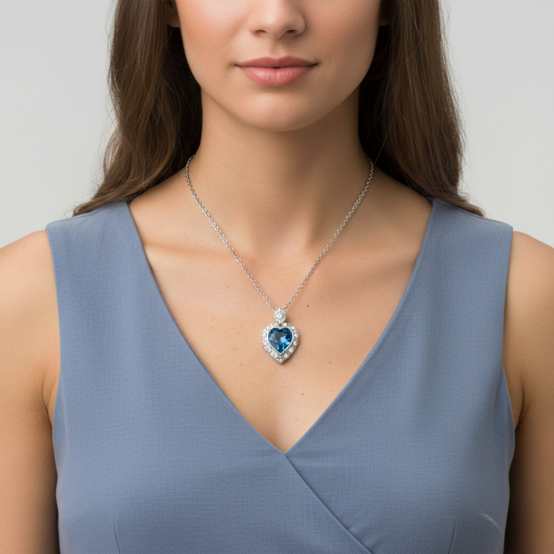 Woman wearing a blue dress with a heart-shaped necklace featuring a blue gemstone.