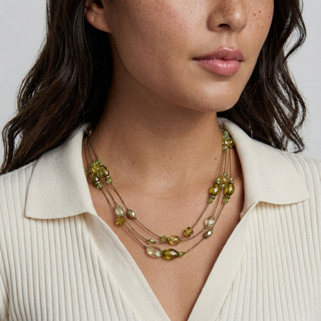 Woman wearing a layered olivine green beaded necklace on a plain background
