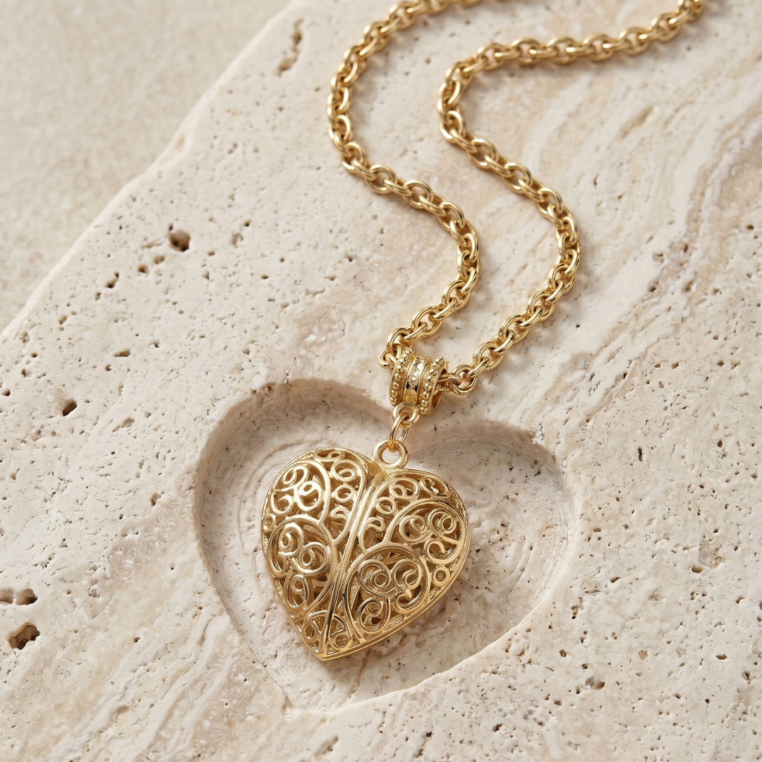 Gold heart pendant necklace resting on a light stone surface