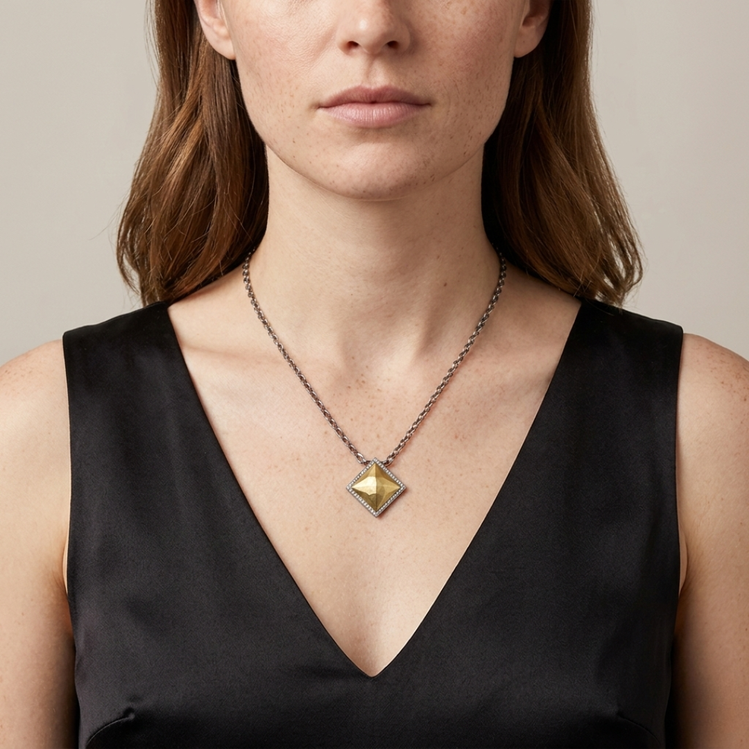Woman wearing a necklace with a shiny geometric fusion lux pendant against a neutral background