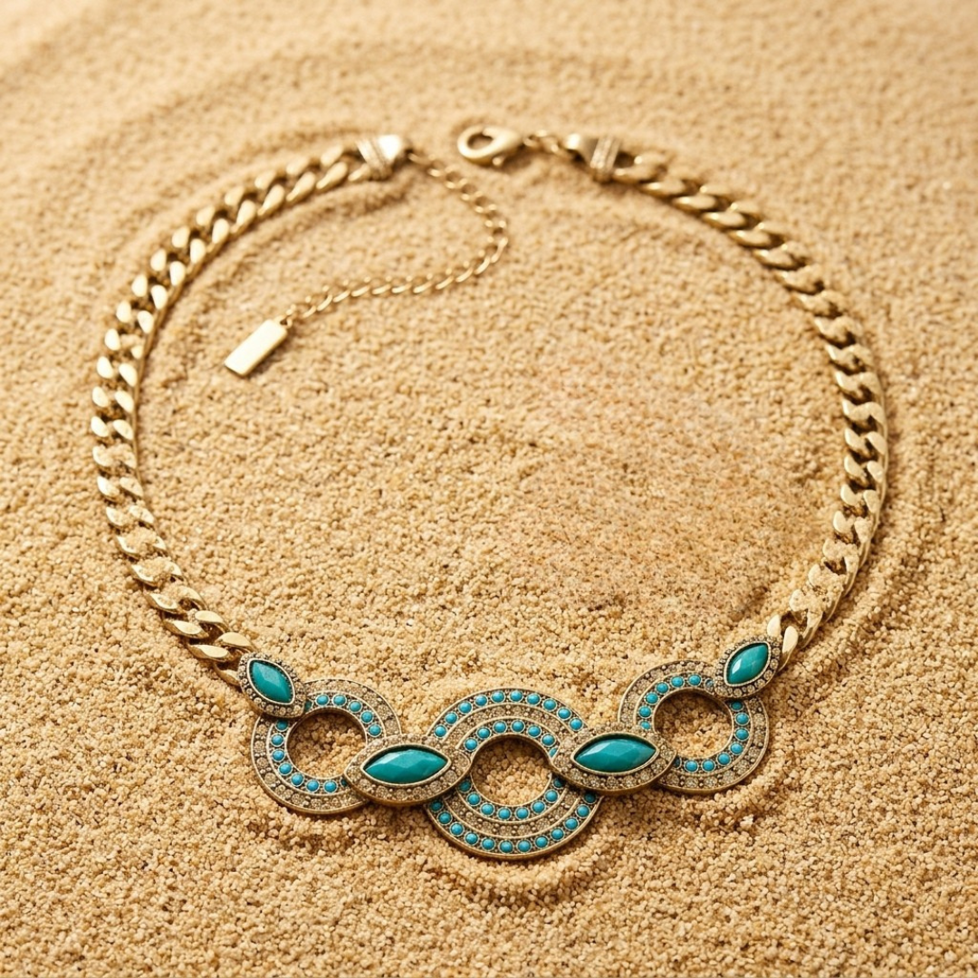 Gold necklace with turquoise stones on a sandy background