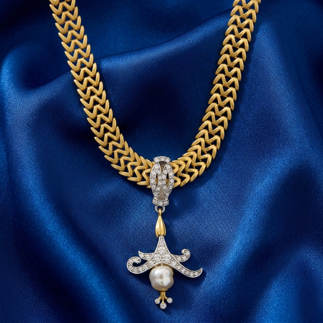 Gold chain necklace with crystals and a faux pearl pendant on blue satin fabric