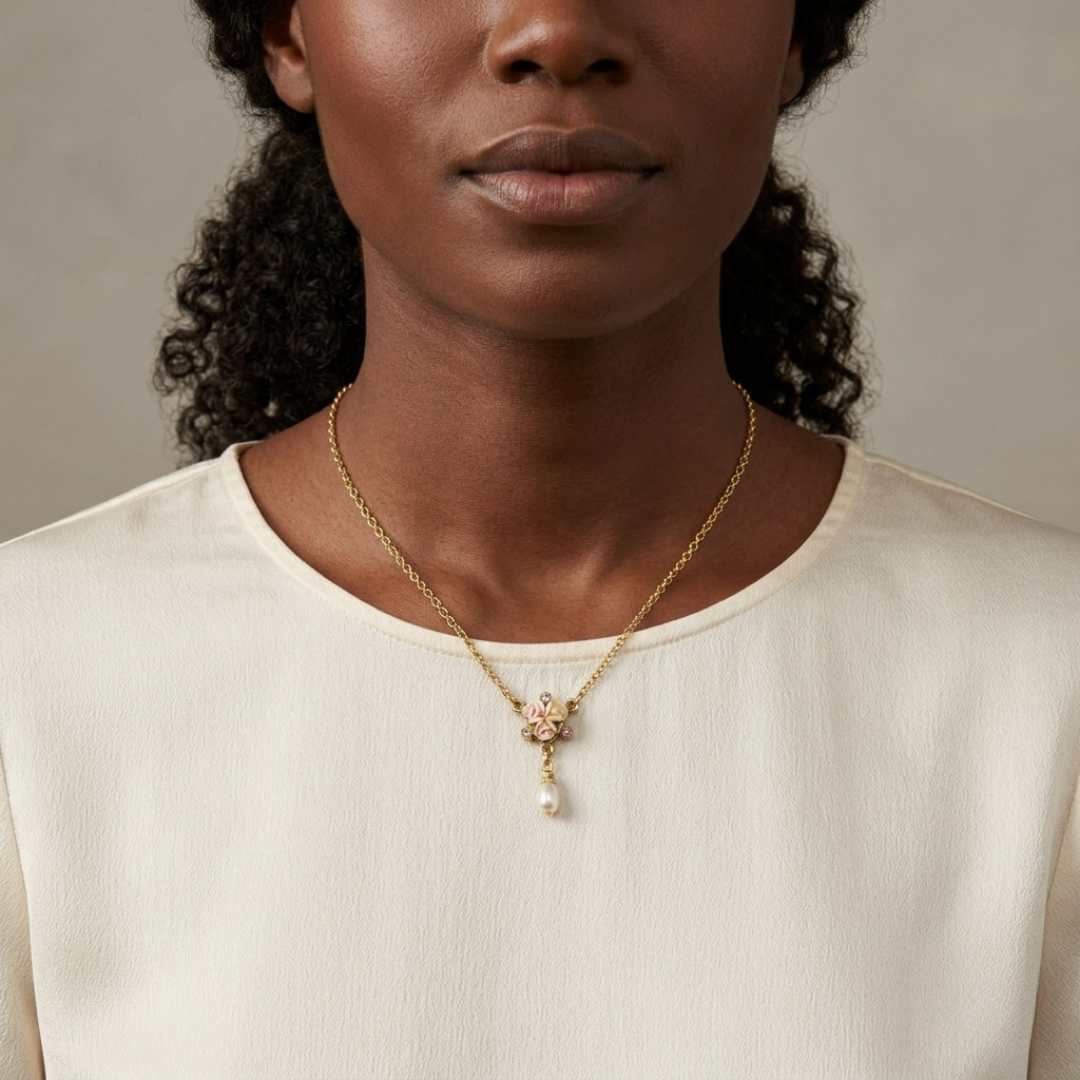 Woman wearing a gold necklace with a floral porcelain rose and faux pearl pendant on a neutral background