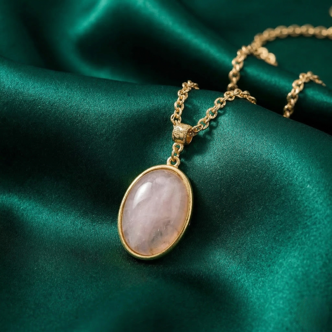 Gold necklace with a pink stone pendant on green satin fabric