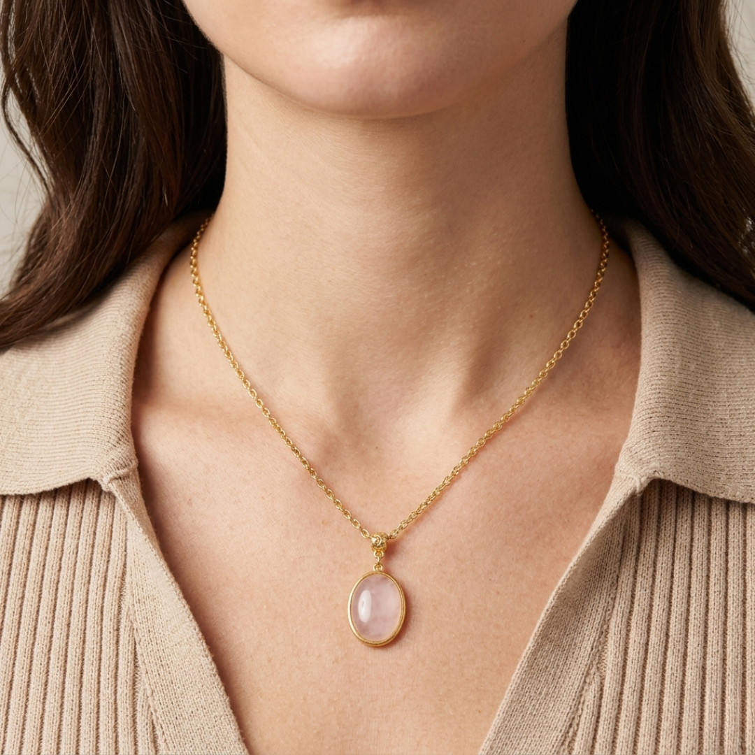 Gold necklace with a Rose Quartz gemstone pendant worn by a person in a beige sweater.