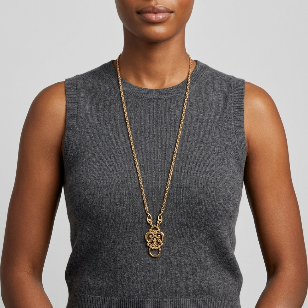 Woman wearing a gold eye glass holder necklace with a gray sleeveless top on a light gray background