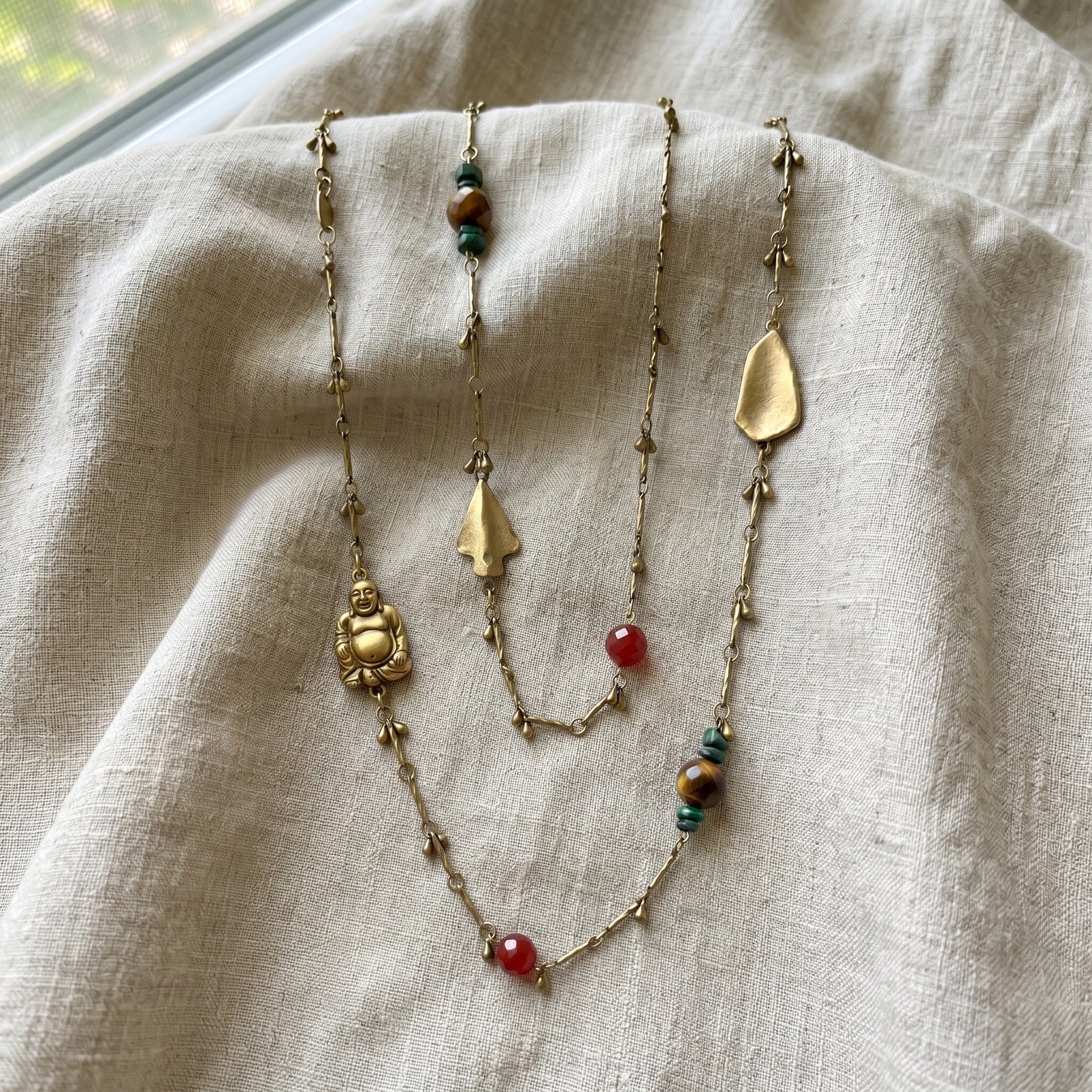 Droplet Chain With Buddha And Gemstone Accents Necklace on light linen fabric