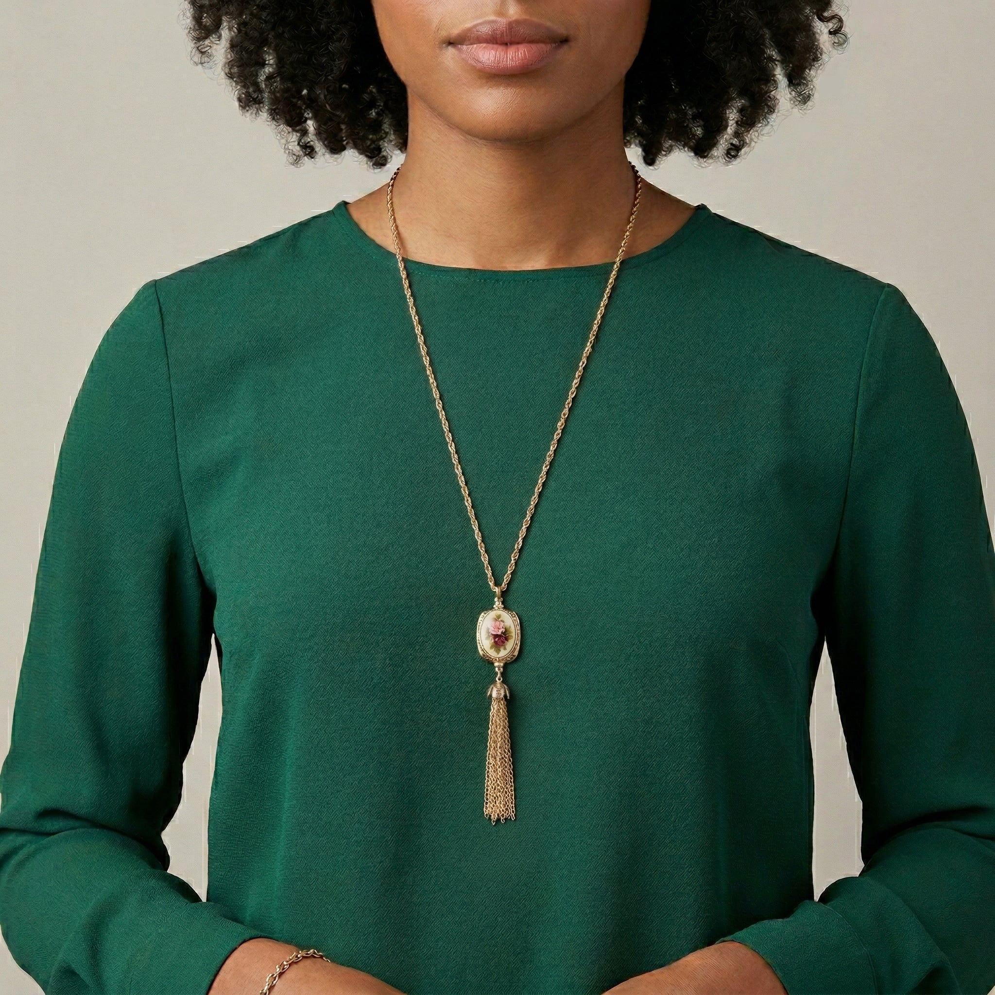 Woman wearing a green top and a Manor House Ivory 3-Sided Roses Spinner Tassel Y-Necklace