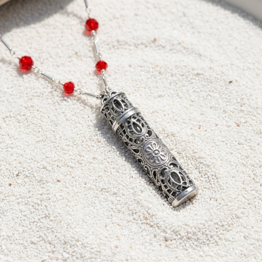 Silver Tone Filigrana Glass Vial Red Beaded Necklace resting neatly on fine white sand