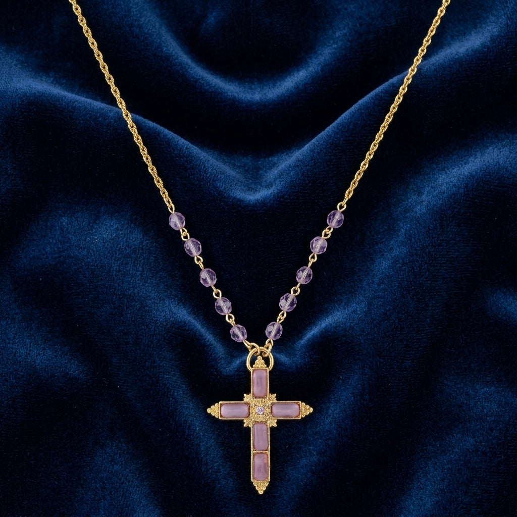 Gold necklace with purple stones and a cross pendant on a blue fabric background