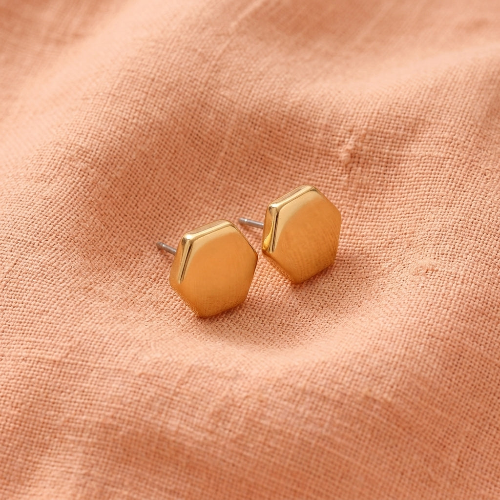 Gold Hexagon Post Button Earrings resting on peach linen