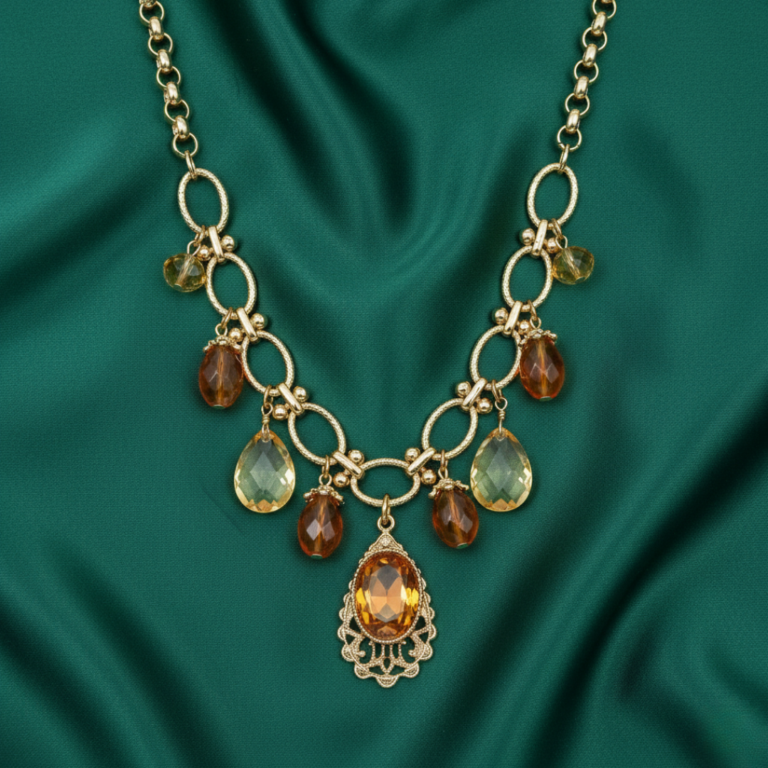 Gold necklace with teardrop-shaped gemstones on a green satin background