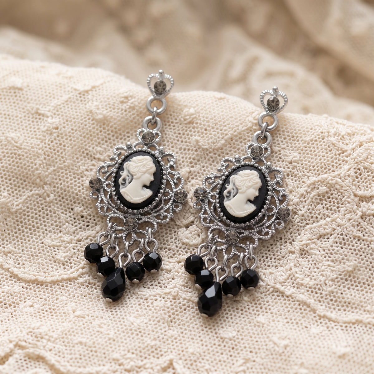 Black Cameo Crystal Beaded Post Drop Chandelier Earrings resting on vintage style laced fabric