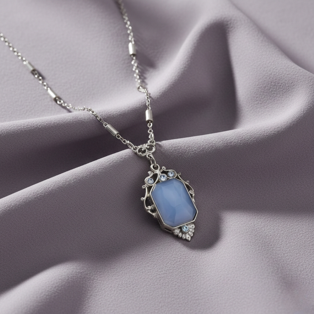 Necklace with a blue pendant on a soft pink fabric background