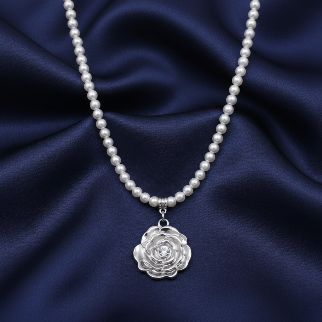 Faux pearl necklace with a silver rose pendant on a dark blue fabric background