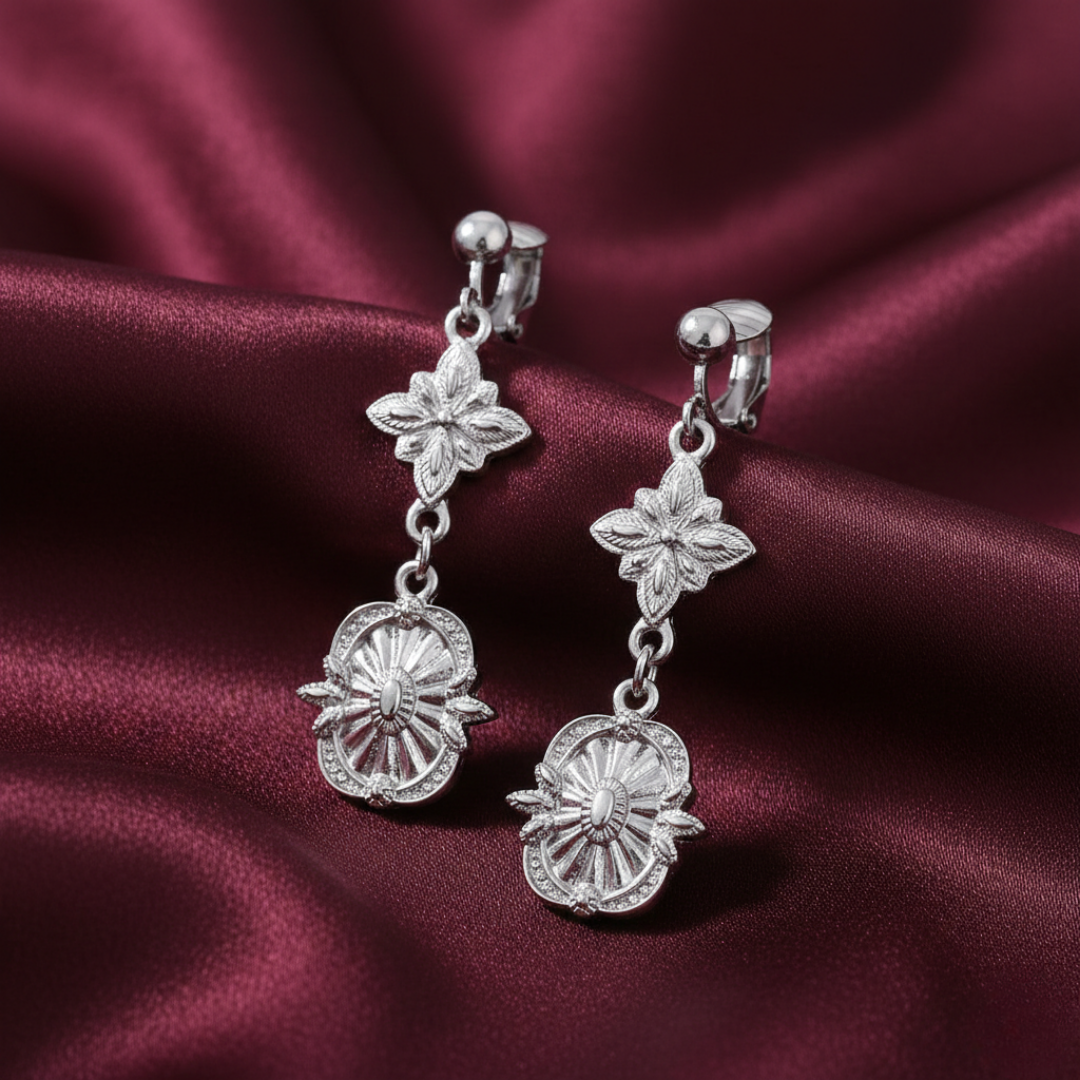 Silver floral earrings on a burgundy satin background