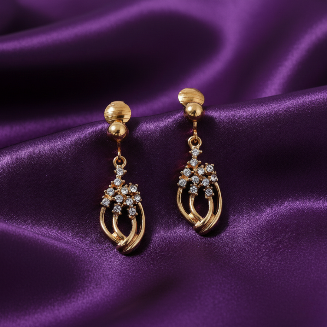 Gold earrings with crystal accents on a purple satin background