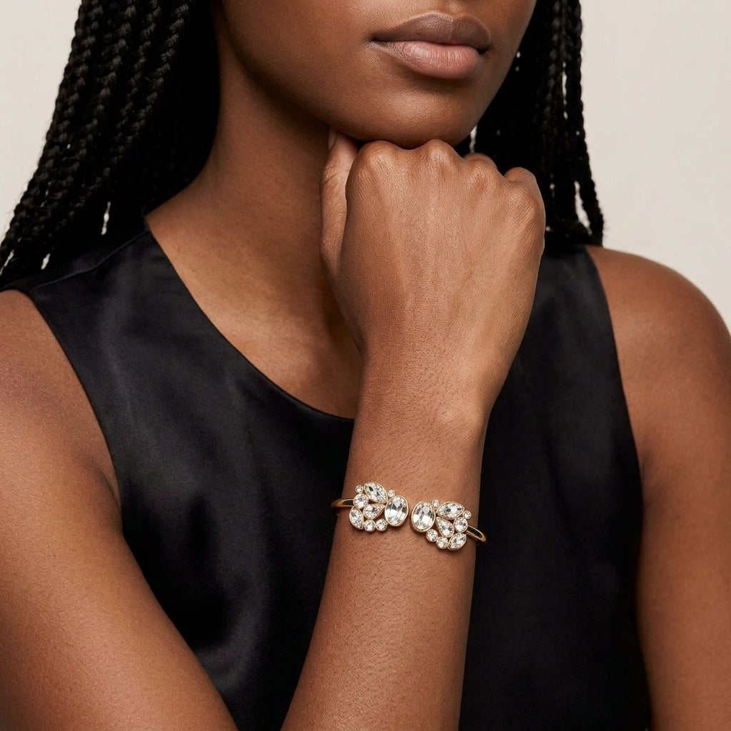Woman in a black top wearing a gold tone spring bracelet with over a dozen sparkling clear crystals