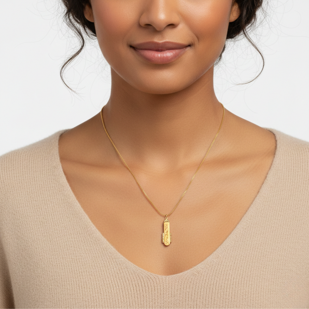Woman wearing a gold necklace with a pendant on a plain background