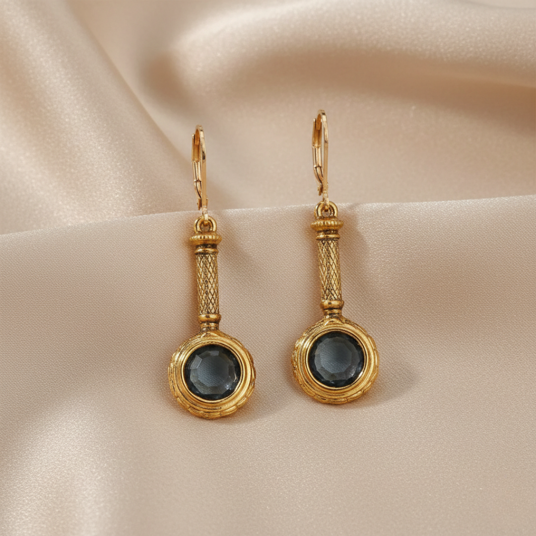 Gold earrings with blue crystals on a beige fabric background