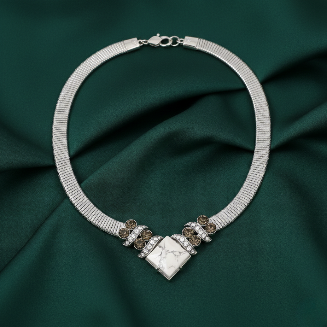 Silver necklace with decorative elements on a dark green fabric background