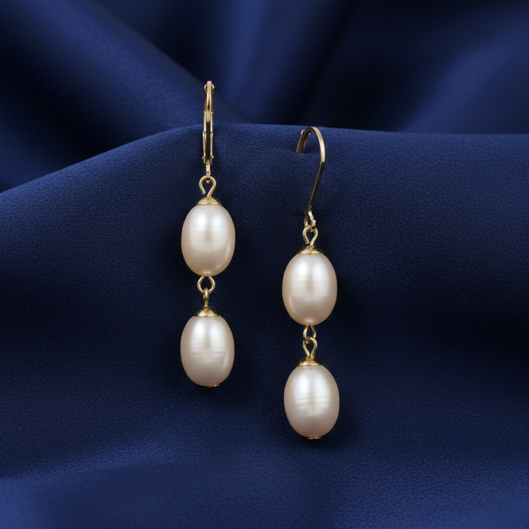 Pearl earrings with gold hooks on a blue fabric background