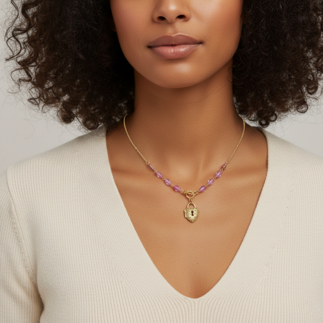 Woman wearing a gold necklace with a heart pendant on a neutral background