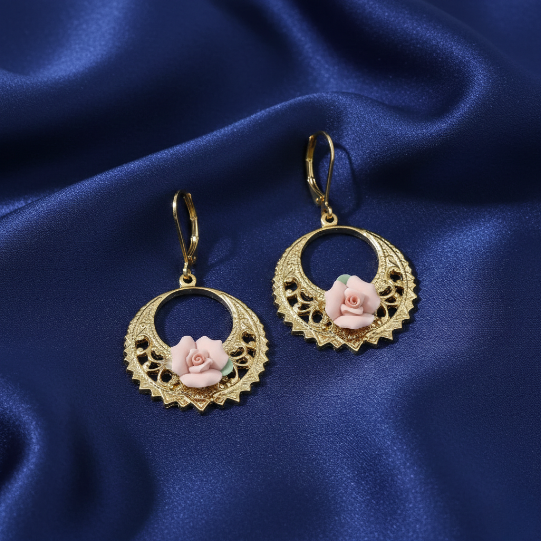 Gold earrings with floral porcelain rose designs on a blue satin background