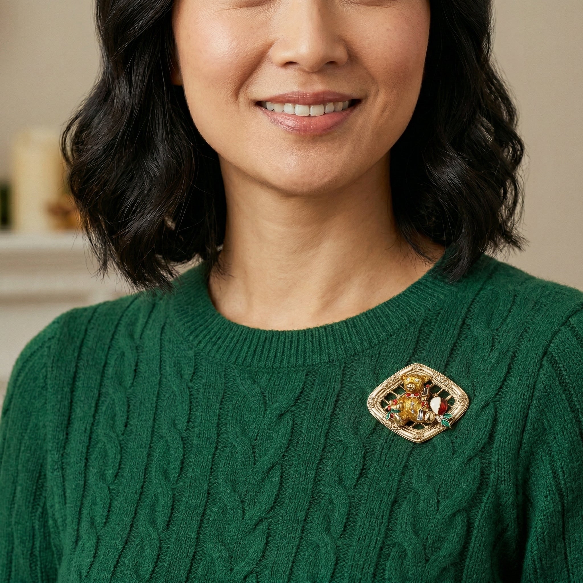 Woman wearing a green sweater with a decorative teddy bear holiday brooch on a neutral background