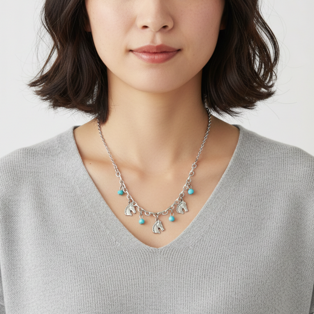 Woman wearing a silver necklace with heart-shaped charms on a plain background