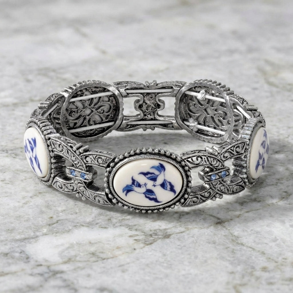 Decorative silver bracelet with blue and white patterns on a marble surface