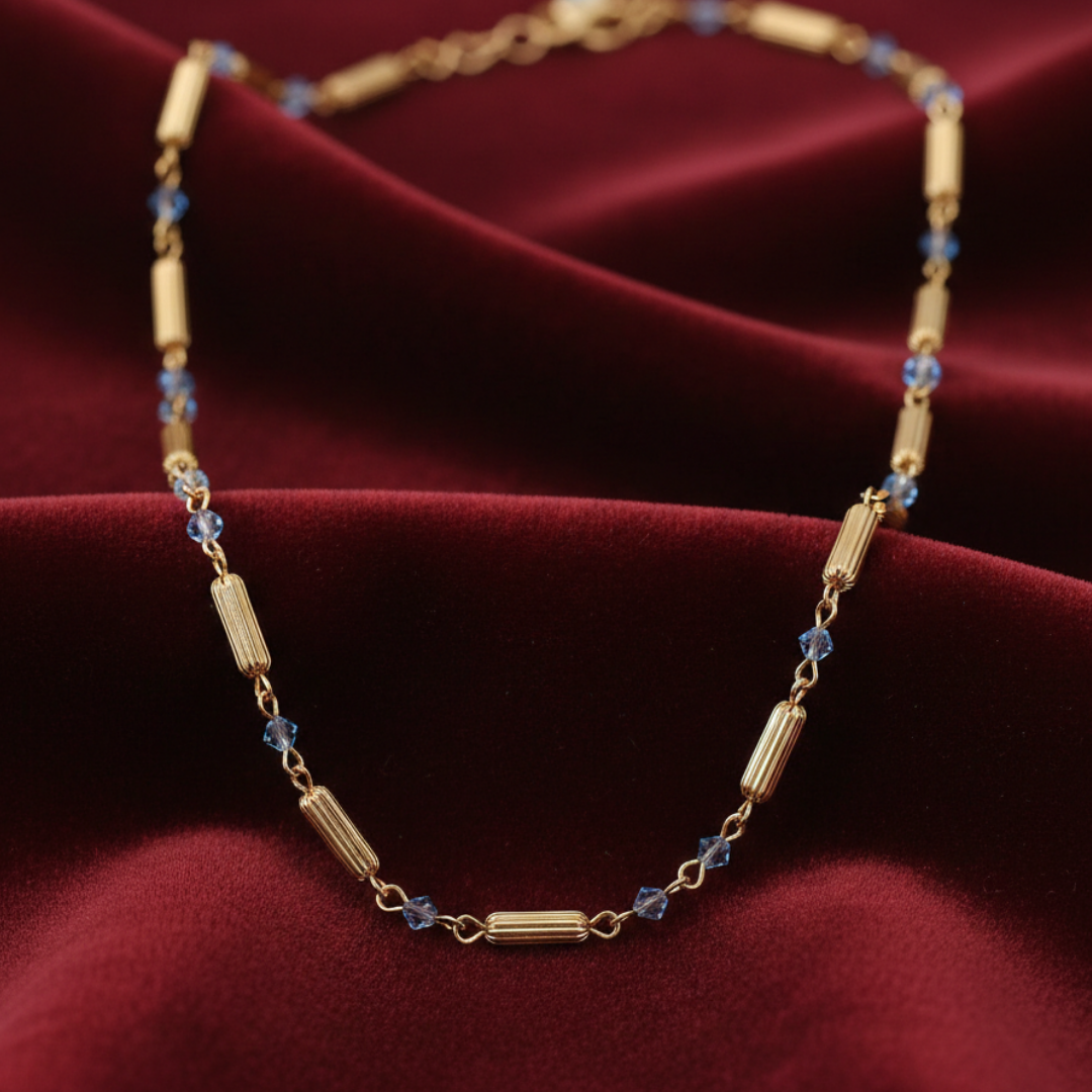Gold necklace with blue beads on a red fabric background