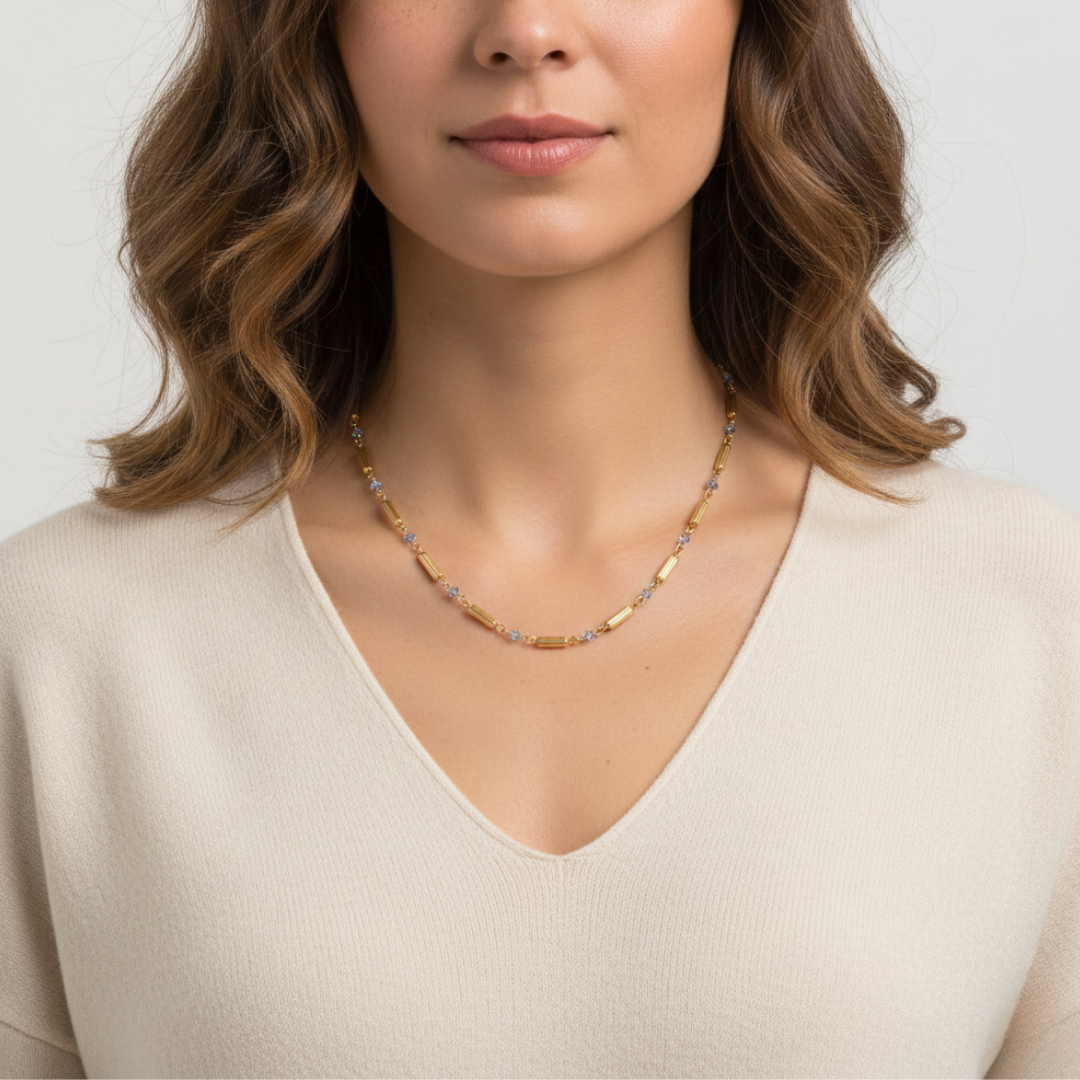 Woman wearing a gold necklace against a plain background