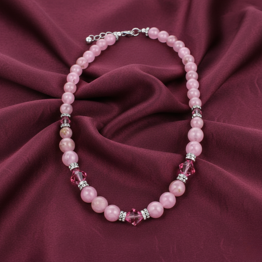 Pink beaded necklace on a maroon fabric background