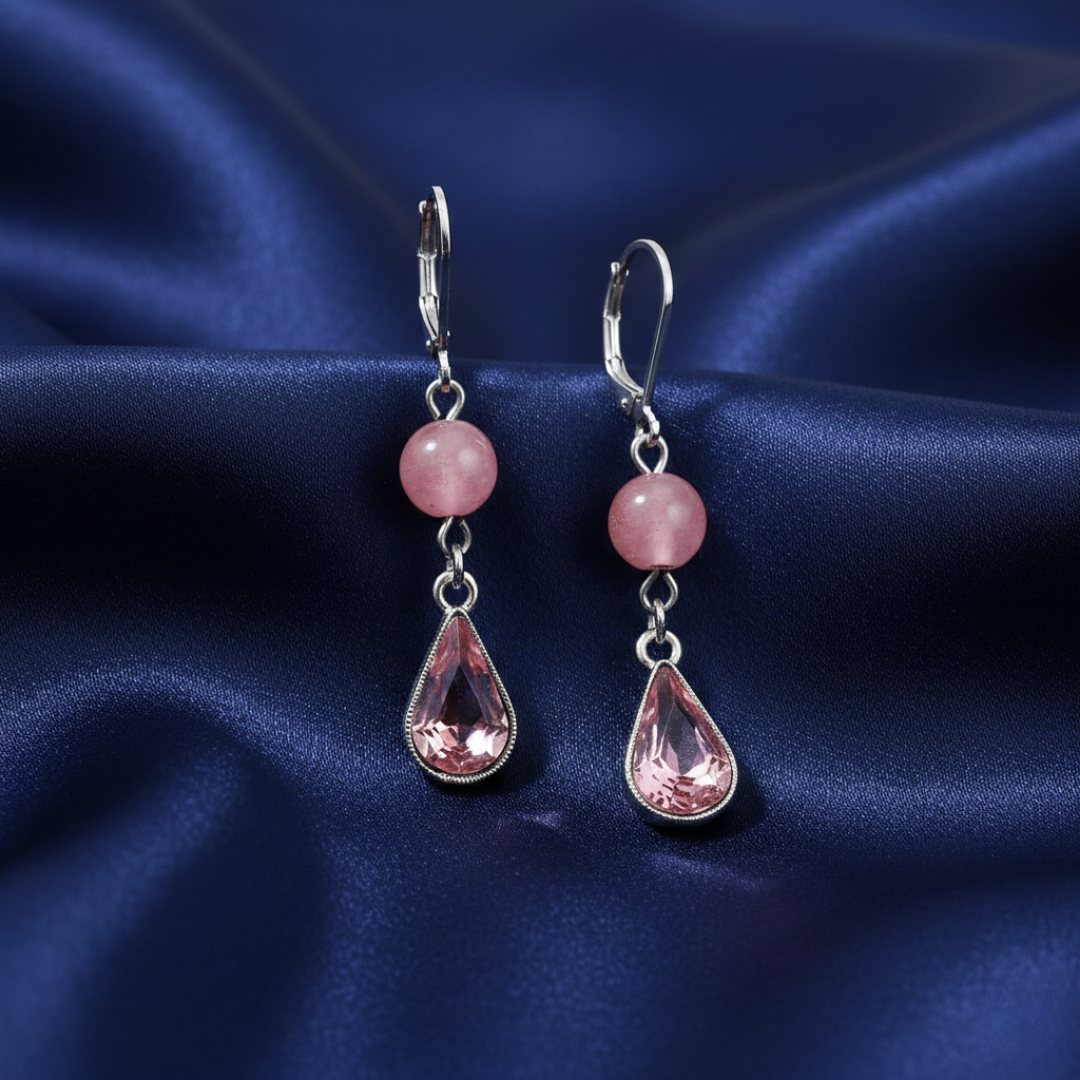 Pair of earrings with pink teardrop-shaped crystals on a blue satin background