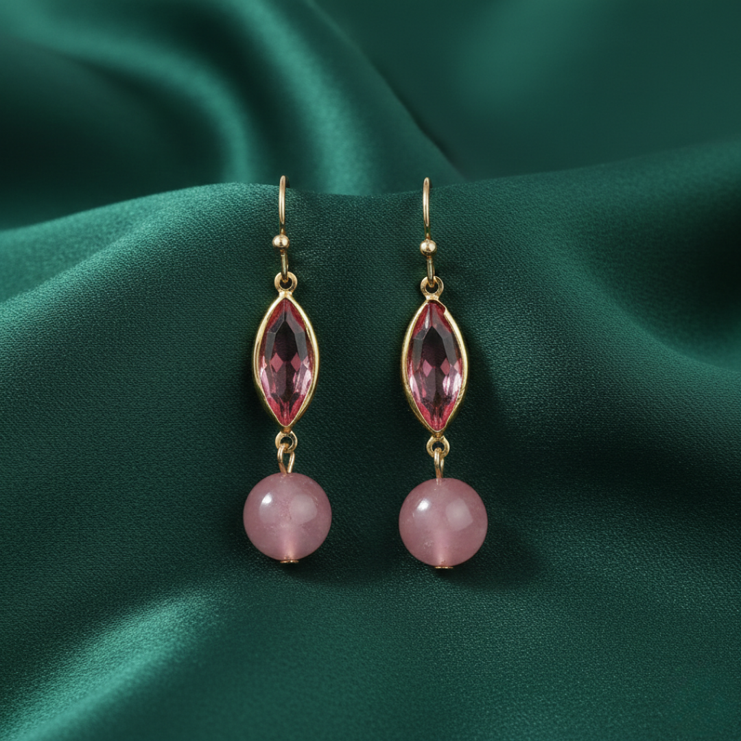 Pair of earrings with pink gemstones and crystals on a green fabric background