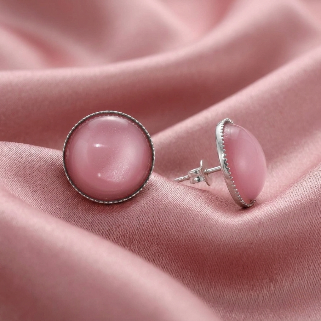 Pink gemstone earrings with silver settings on a pink fabric background