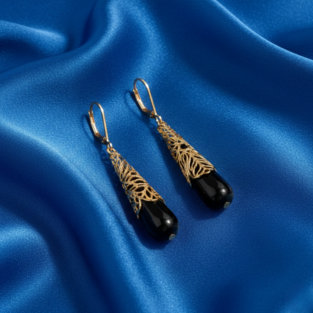 Gold and black earrings on a blue satin background