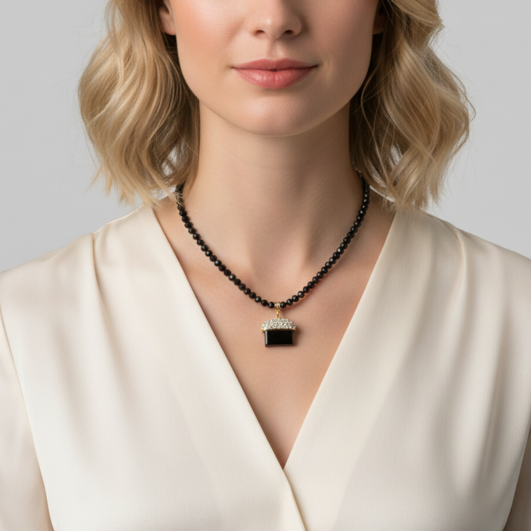 Woman wearing a black beaded necklace with a pendant against a neutral background