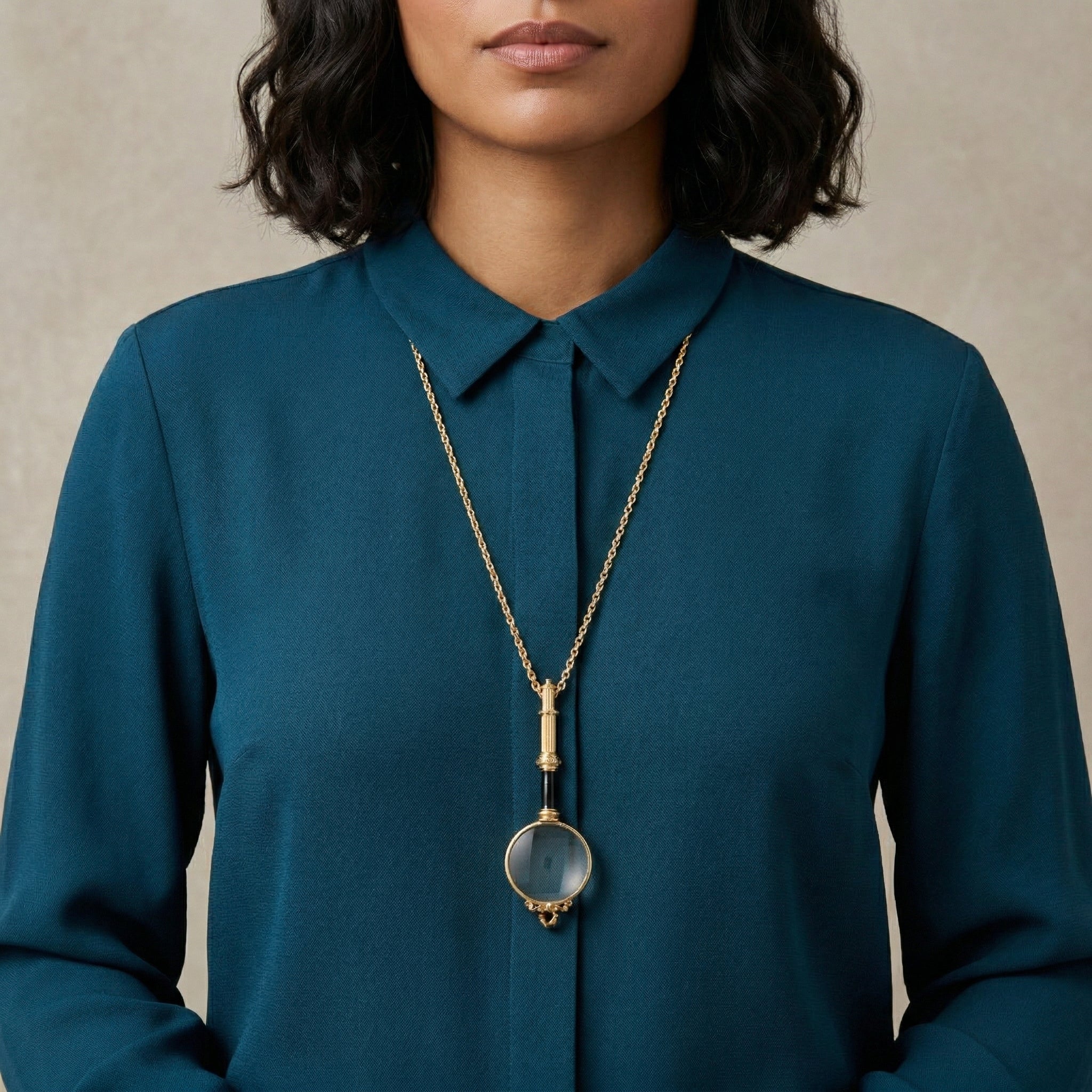 Person wearing a teal shirt with a Golden Era Magnification Pendant Necklace