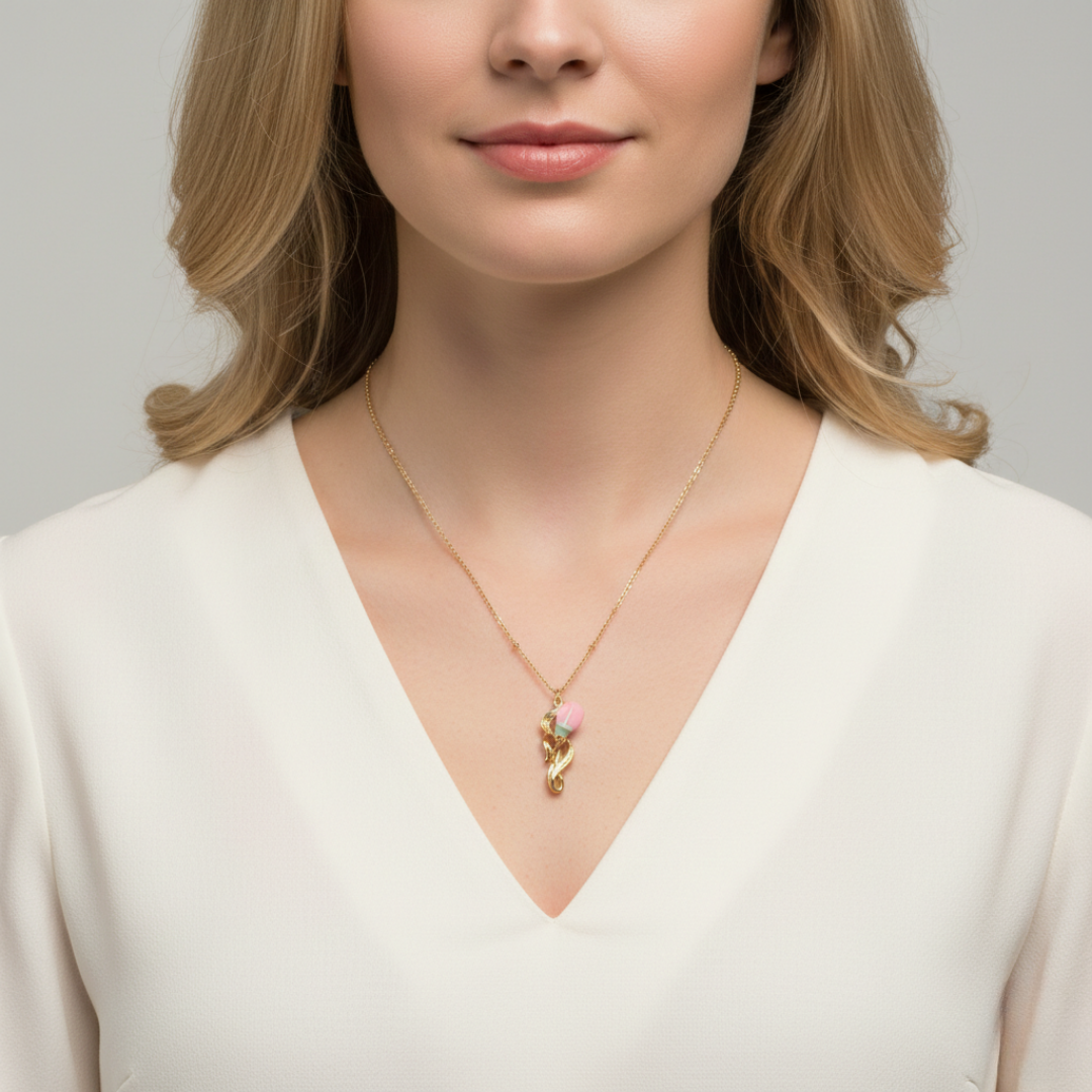 Woman wearing a gold necklace with a rose pink floral pendant.