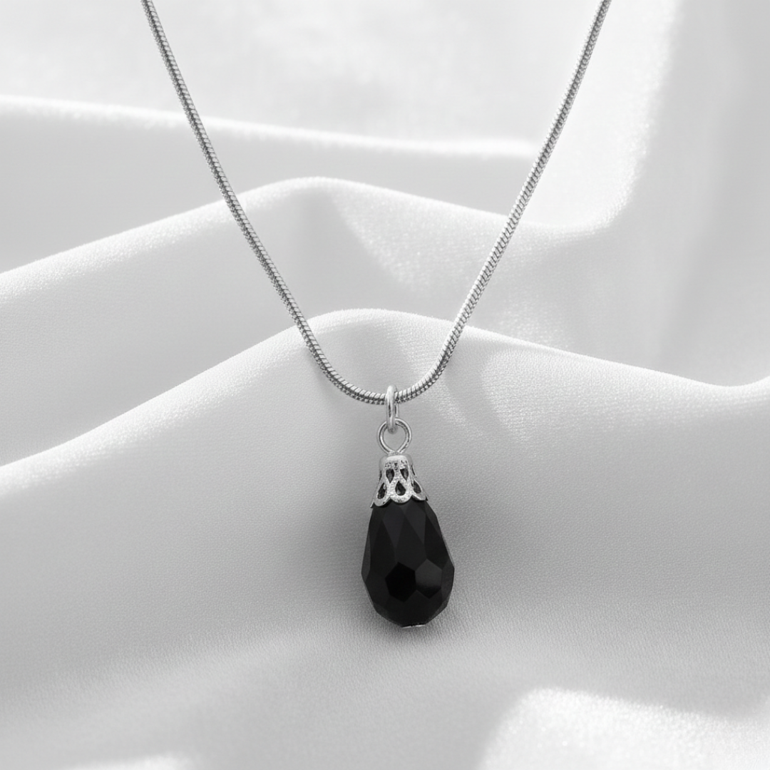 Necklace with a black teardrop pendant on a white fabric background