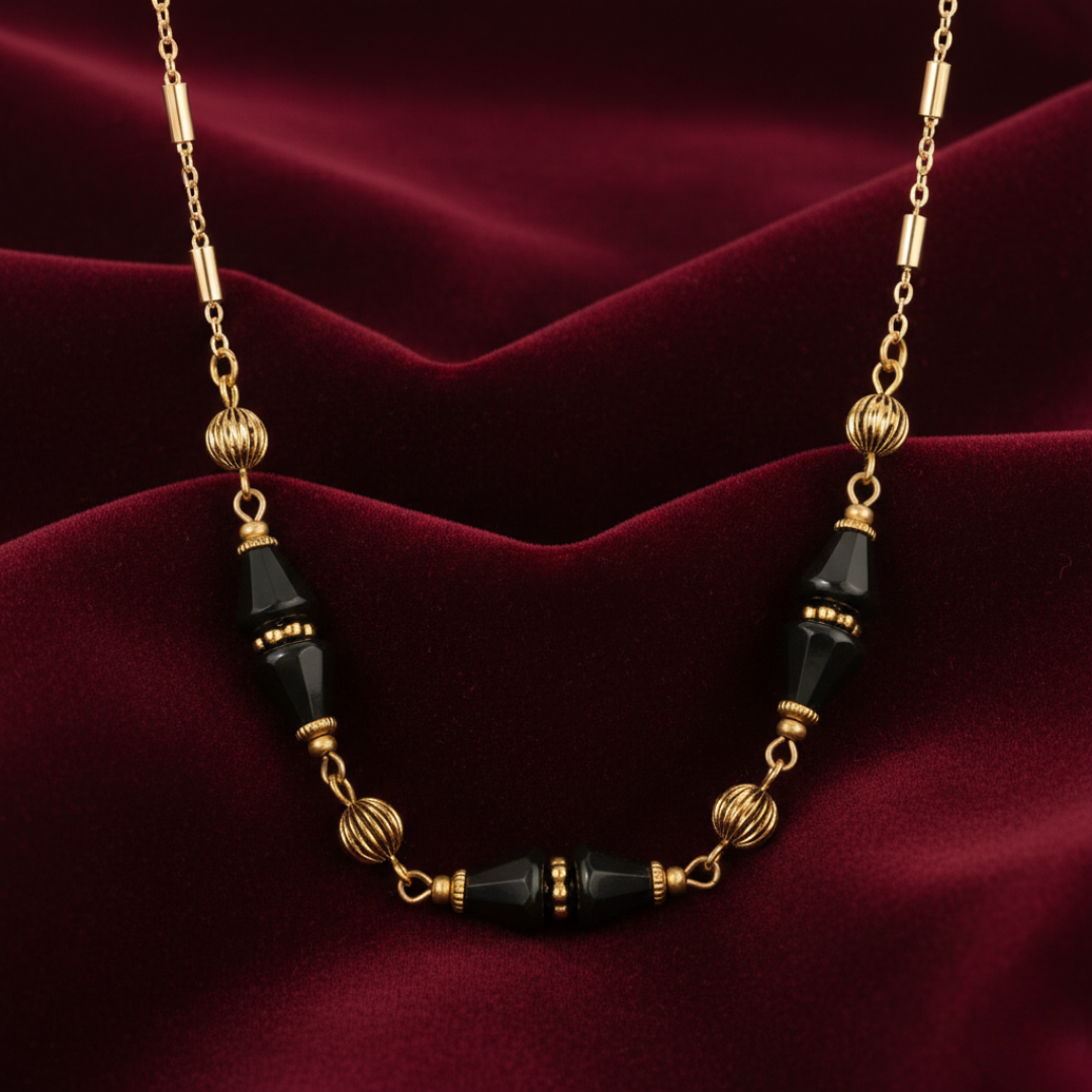 Necklace with gold and black beads on a red fabric background