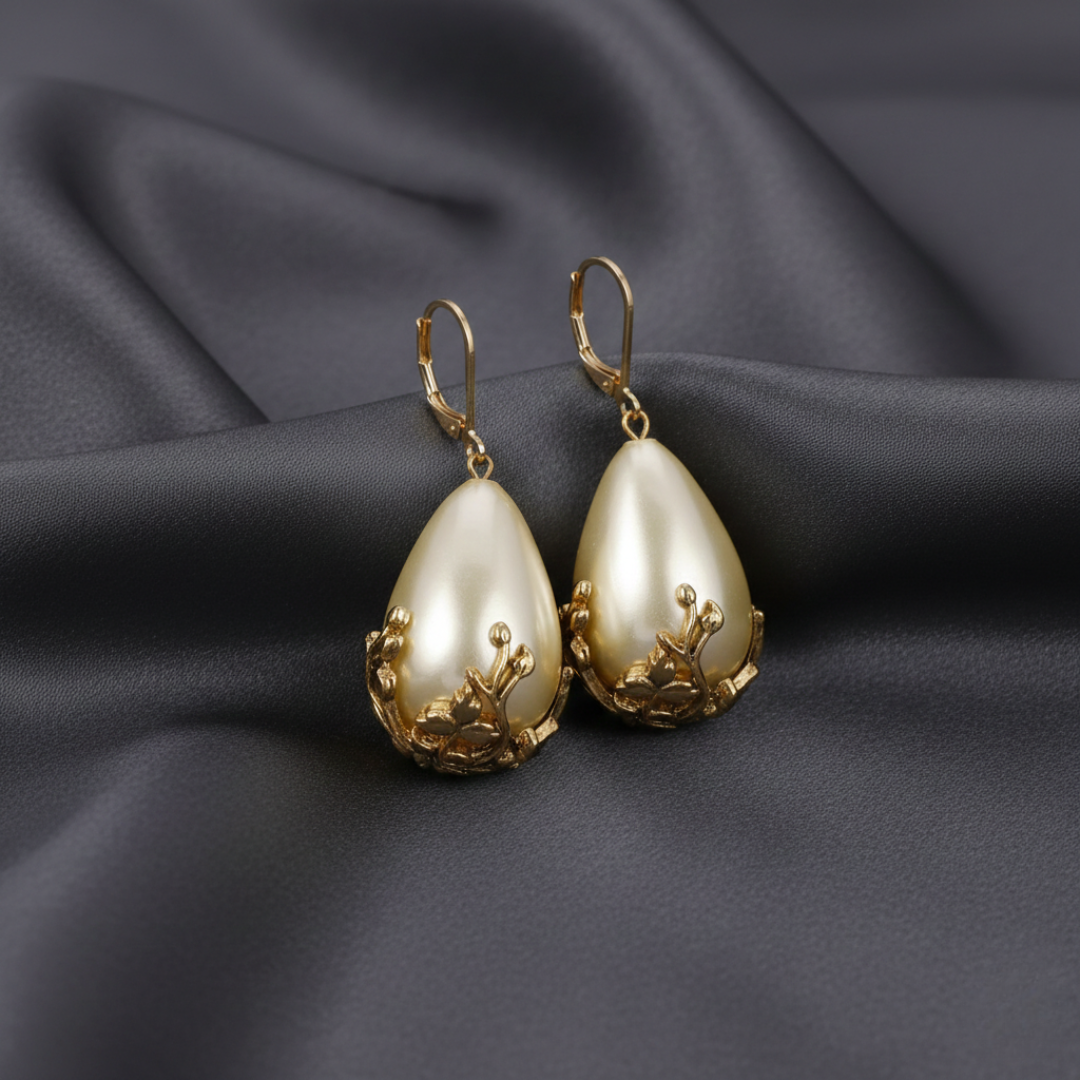 Pair of gold and faux pearl earrings on a dark fabric background