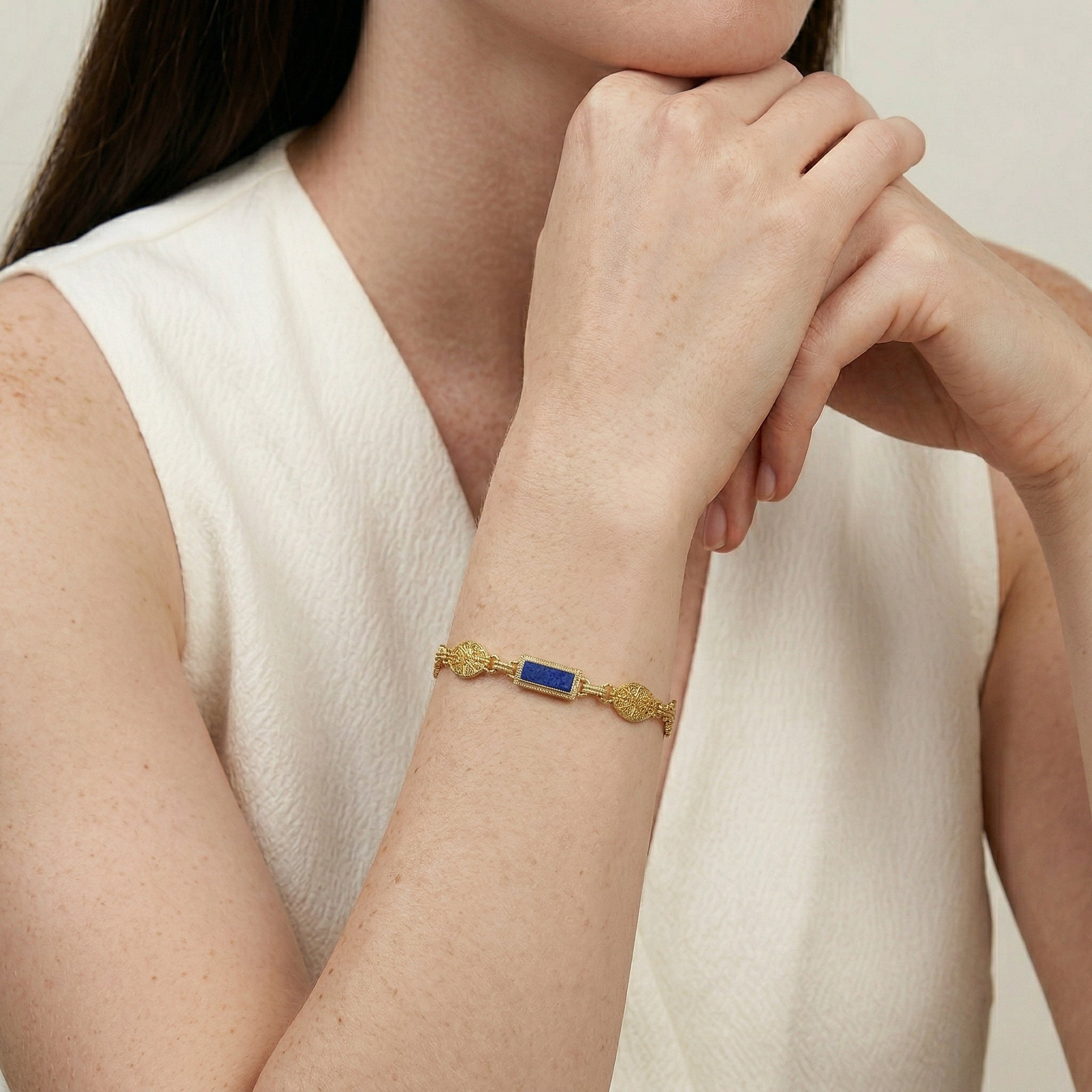 Gold tone and blue Baroque Heirloom Gold Link Bracelet worn by a woman on her wrist