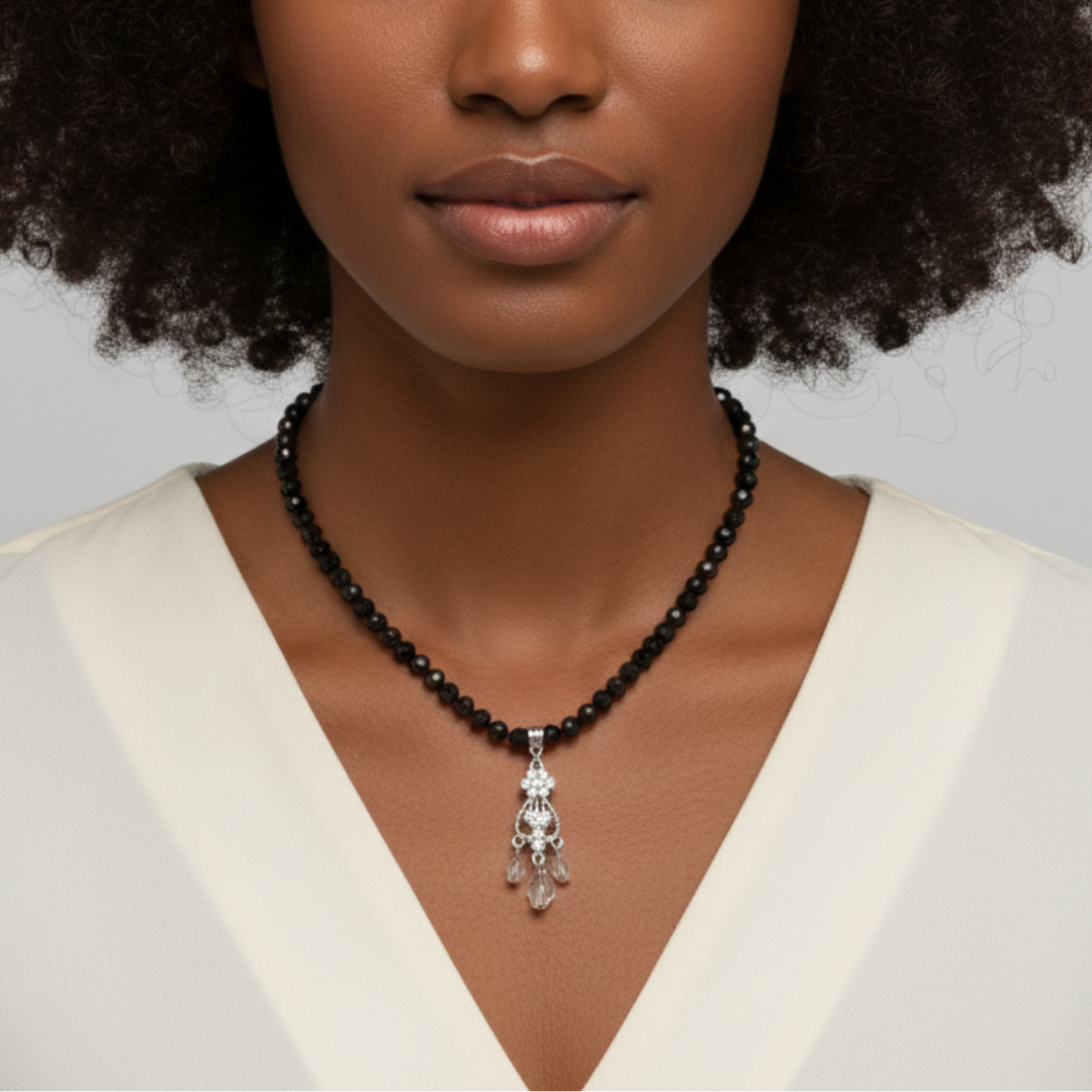 Woman wearing a black beaded necklace with a silver pendant against a neutral background