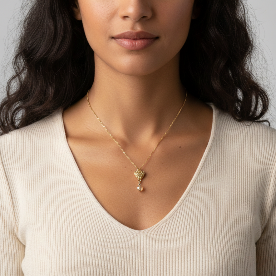 Woman wearing a gold necklace with a heart pendant on a neutral background