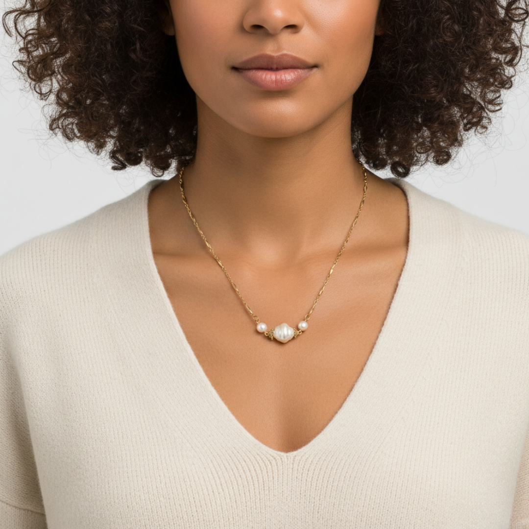 Woman wearing a gold necklace with faux pearls against a neutral background
