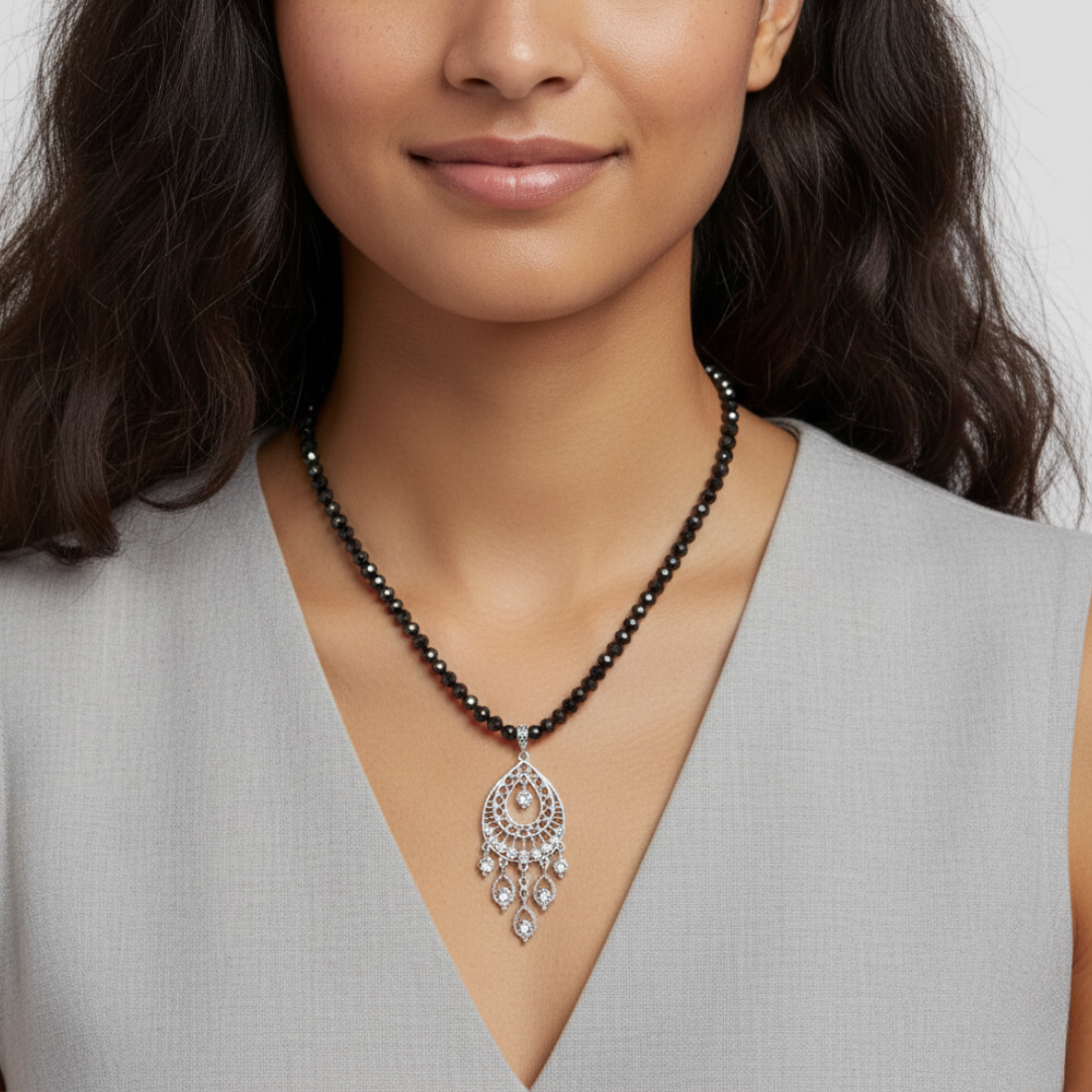 Woman wearing a black beaded necklace with a silver pendant against a neutral background